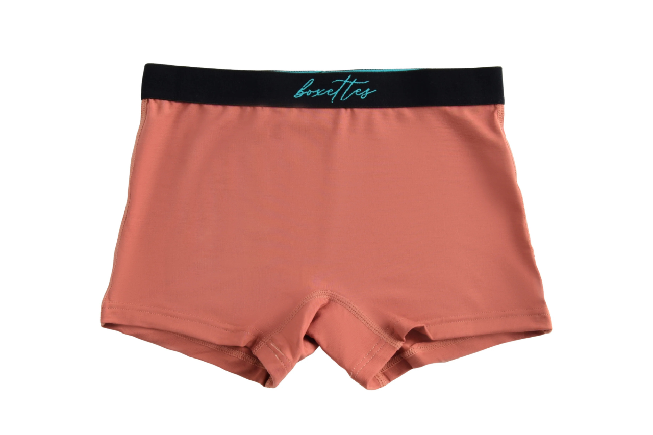 Pair of pink boxer briefs with a black waistband on a white background