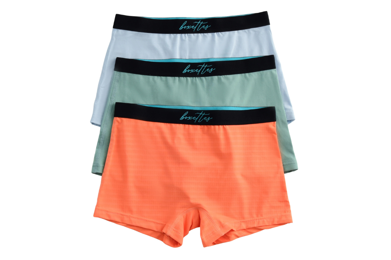 Three pairs of boxer briefs in orange, green, and gray with a brand logo on a white background.