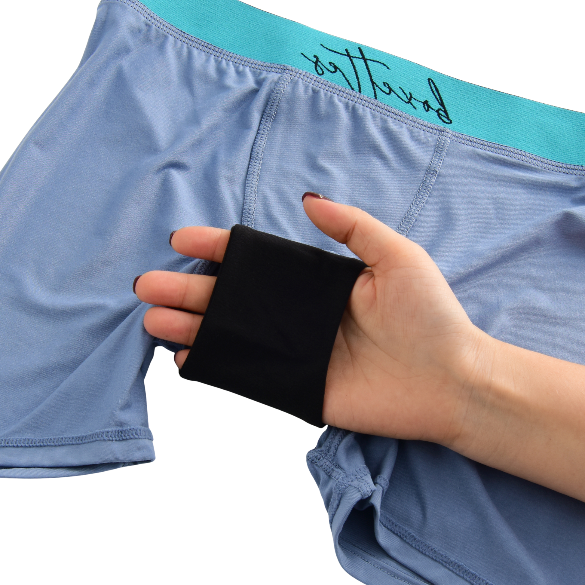 Person holding a black wristband in front of blue underwear with teal waistband.